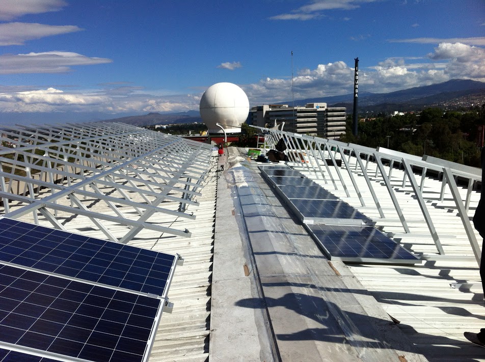 sistema de paneles solares fotovoltaicos instalados en techo con panorama de fondo de la Ciudad de México