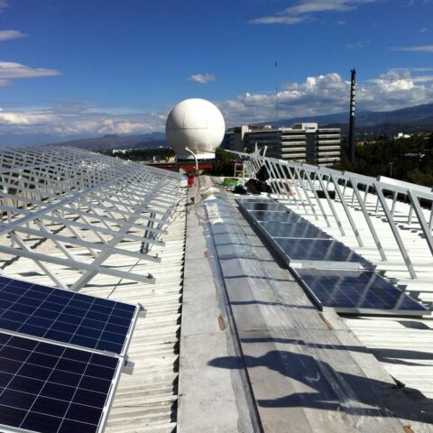 sistema de paneles solares fotovoltaicos instalados en techo con panorama de fondo de la Ciudad de México