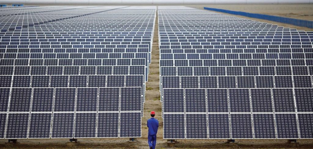 Hombre parado en medio de granja de paneles solares fotovoltaicos