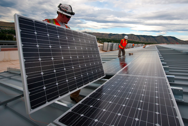 hombres en el tejado de un edificio instalando sistema de paneles solares fotovoltaicos